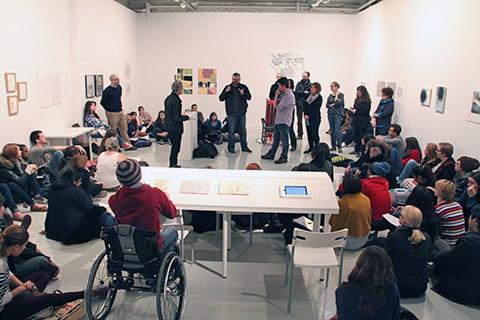 Matt Borgen speaks to a large group of students assembled on the floor or standing in an art gallery