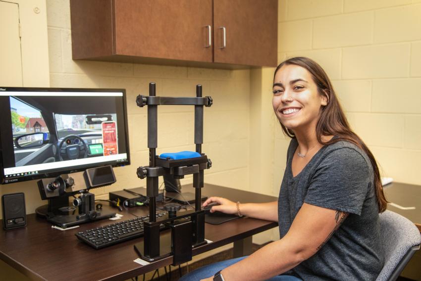 Kayla Sansevere sits at a computer and smiles