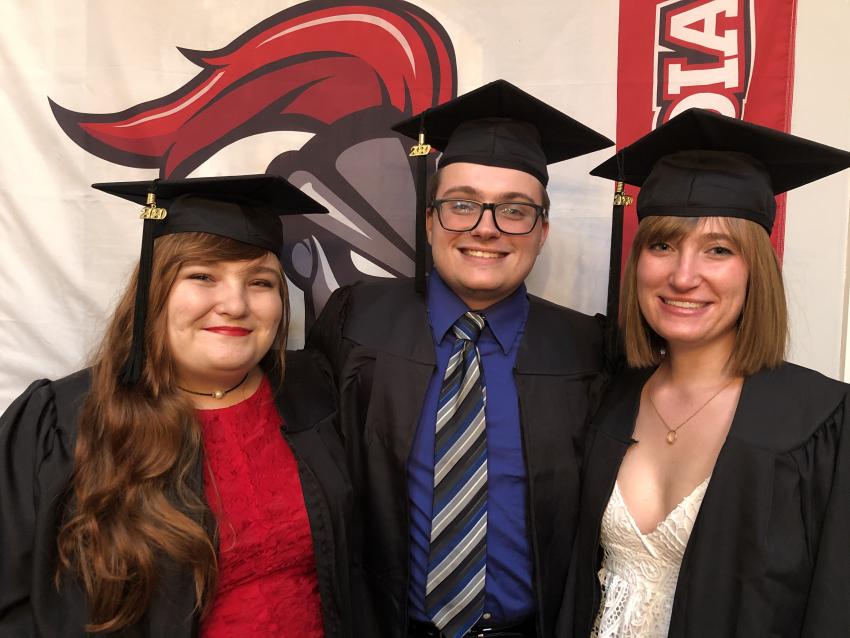 Three students wearing cap and gown