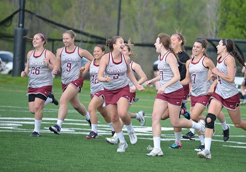 Women's lacrosse players run across the field