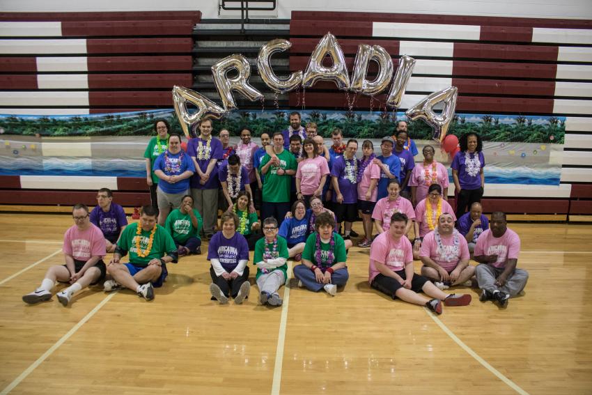 A large group of people in the gymnasium with balloons that spell out "ARCADIA"