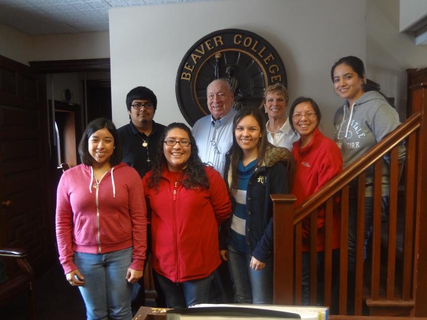 A group poses in Blankley house on the stairs in front of a large Beaver College seal.