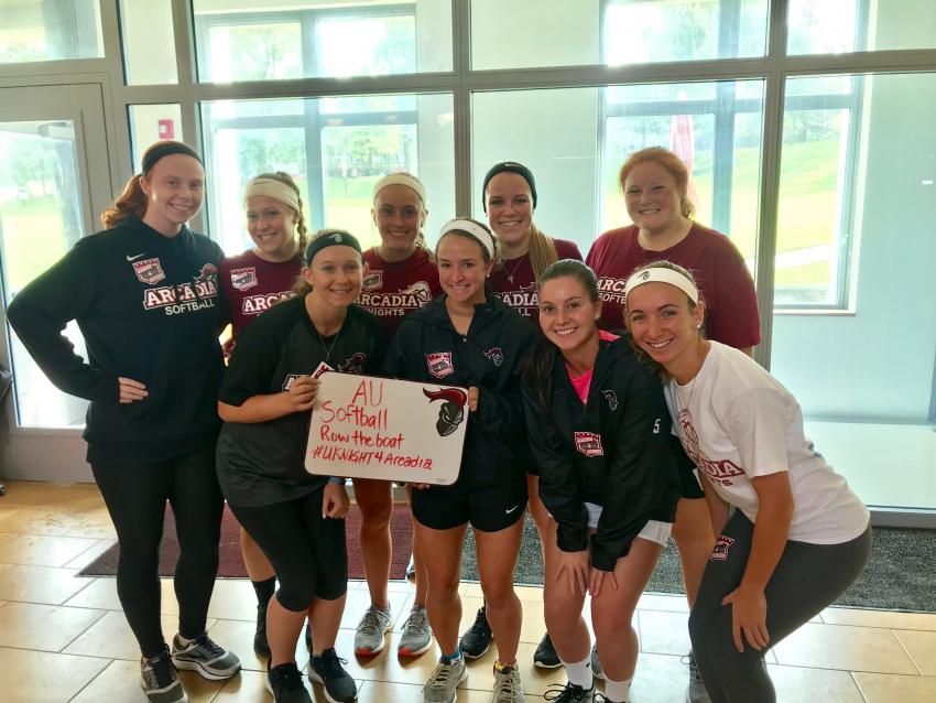 group of softball female athletes posing with AU Softball Row The Boat Sign
