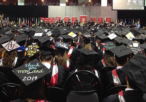 2014 Commencement students sitting back-view of grad caps and stage