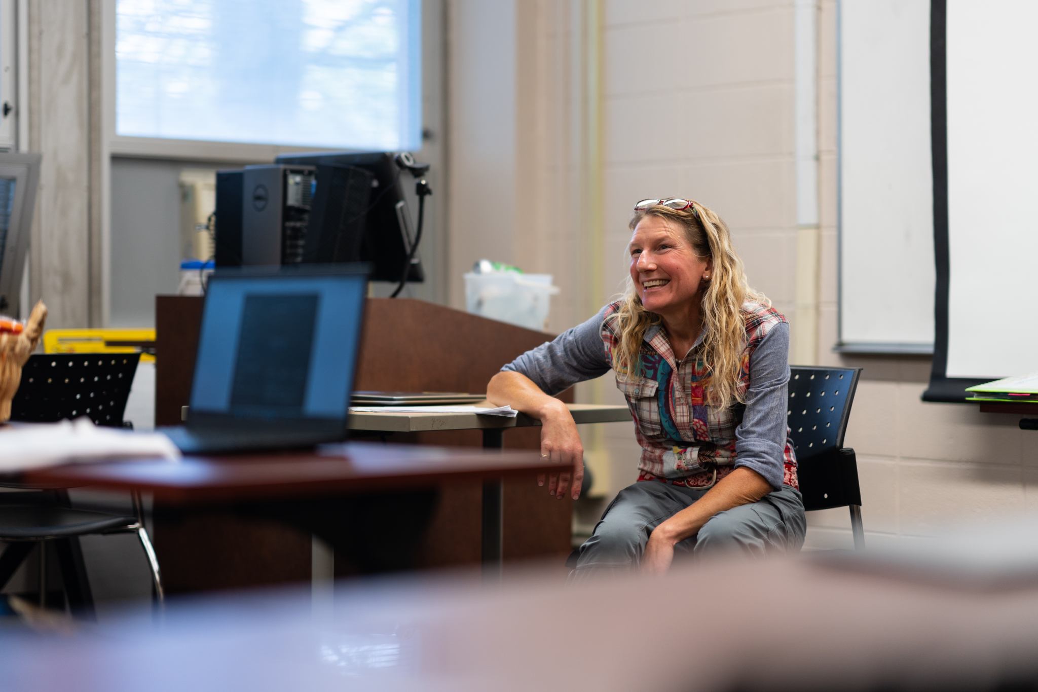 A professor sitting at the front of the classroom.