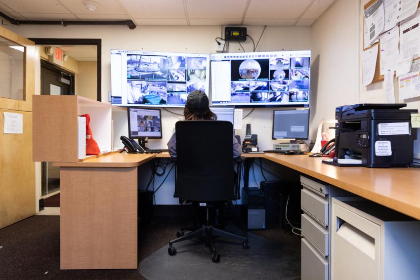 Department of Public Safety specialist at a computer with 5 monitors keeping the campus safe