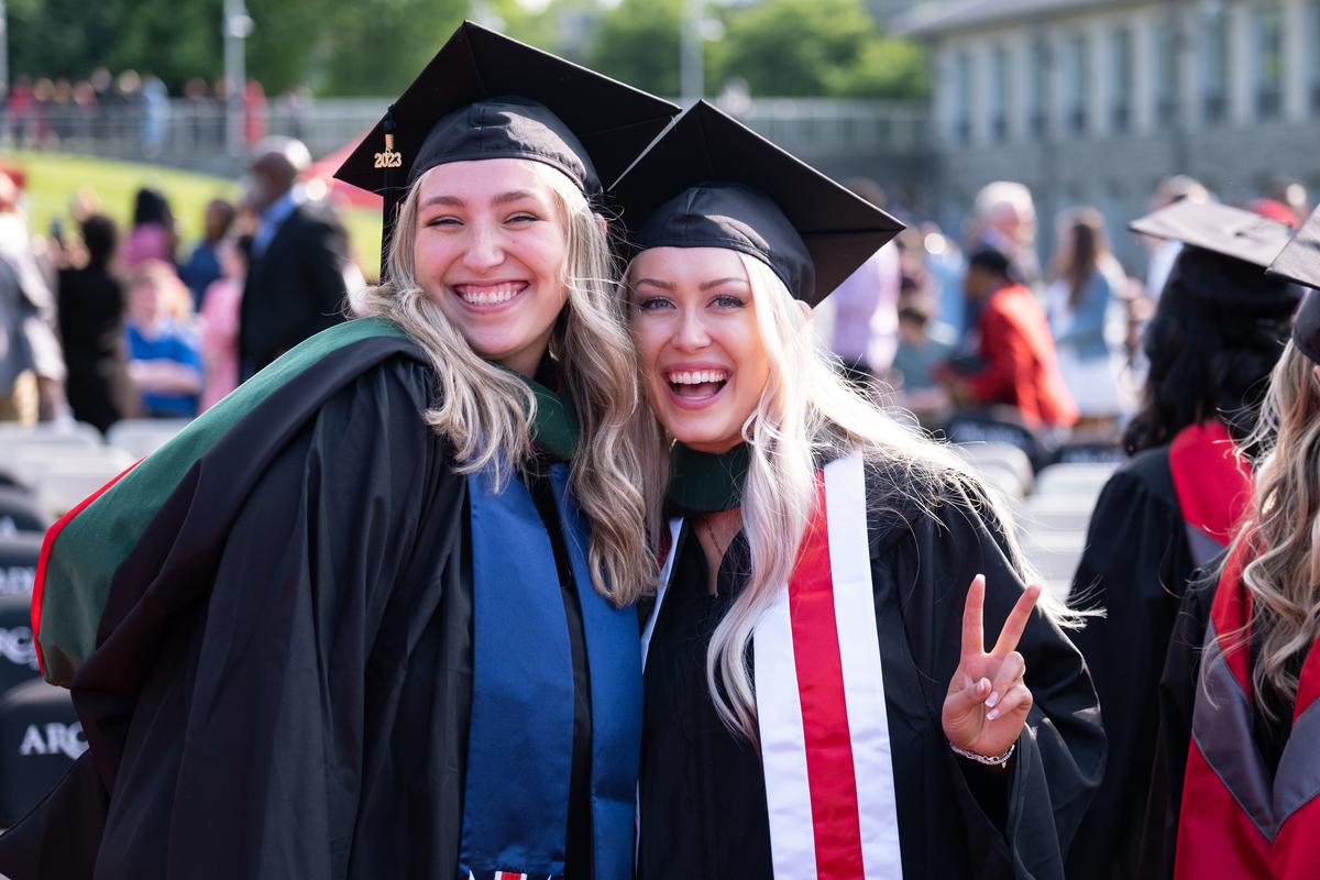Students smiling at the graduate commencement on Haber Green 