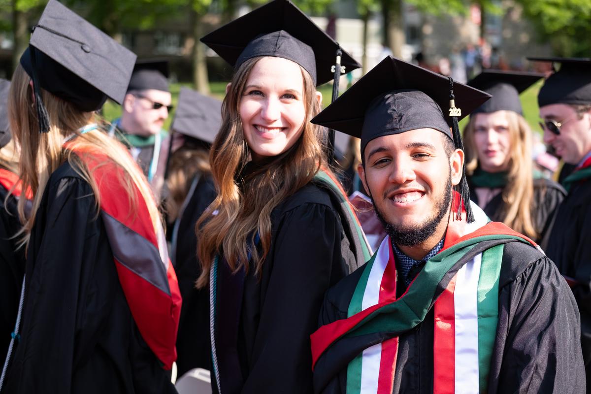 Students smiling at the graduate commencement on Haber Green 