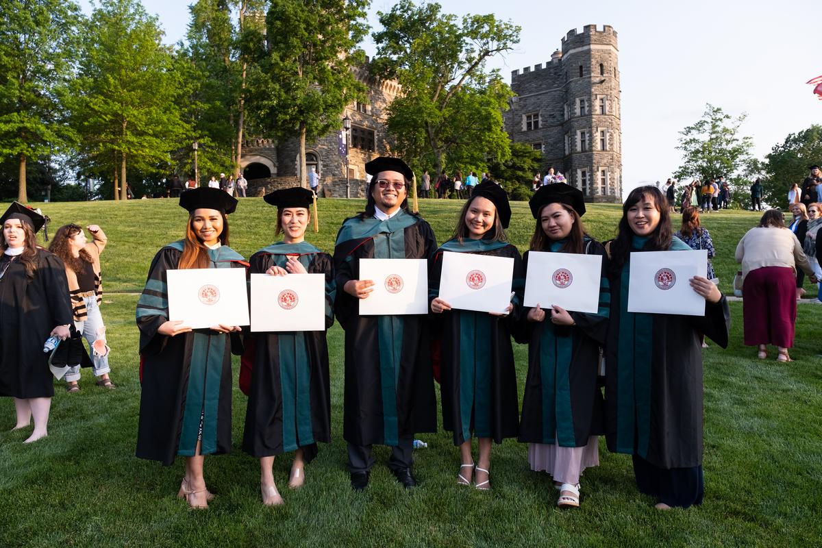 A group of students smiling during during the graduate commencement on Haber Green