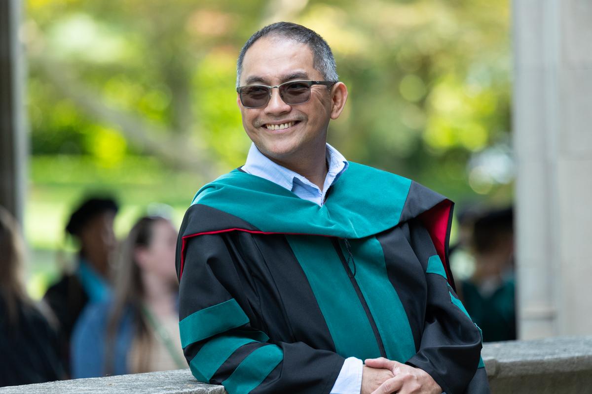 A student smiling during during the graduate commencement on Haber Green