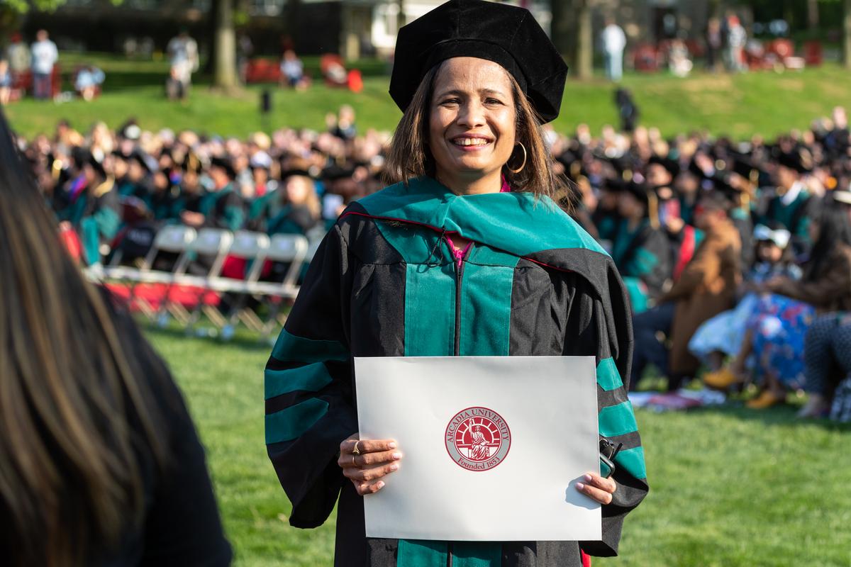 A student smiling during during the graduate commencement on Haber Green