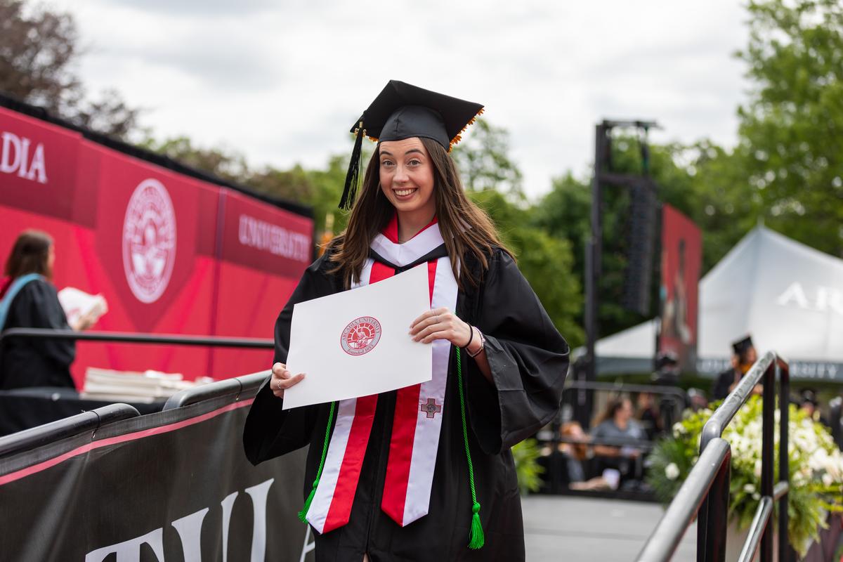 A student smiling during the graduation ceremony on Haber Green 
