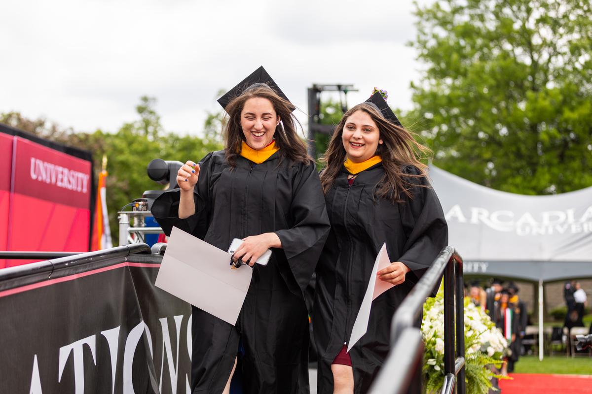 Two students smiling during the graduation ceremony on Haber Green 