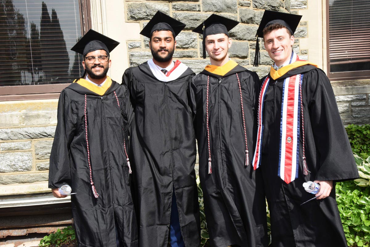 Four students smiling during the graduation ceremony on Haber Green