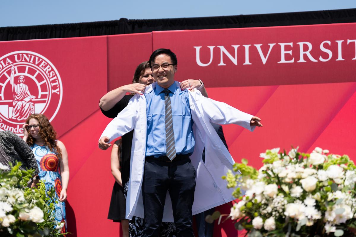 A graduate receives their white coat during the White Coat ceremony