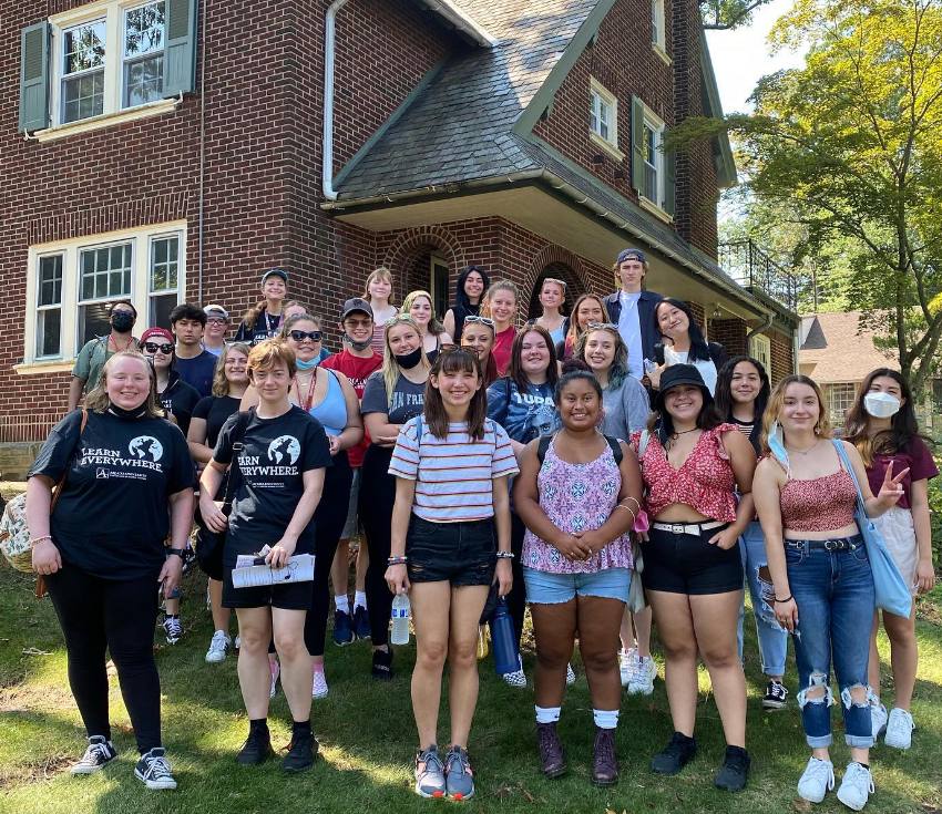 A group of students stand in front of the Civic and Global Engagement House. 