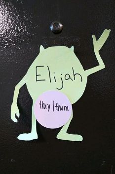 Cut out figure pasted to the author's dorm residence noting the pronoun preference of "they/them."