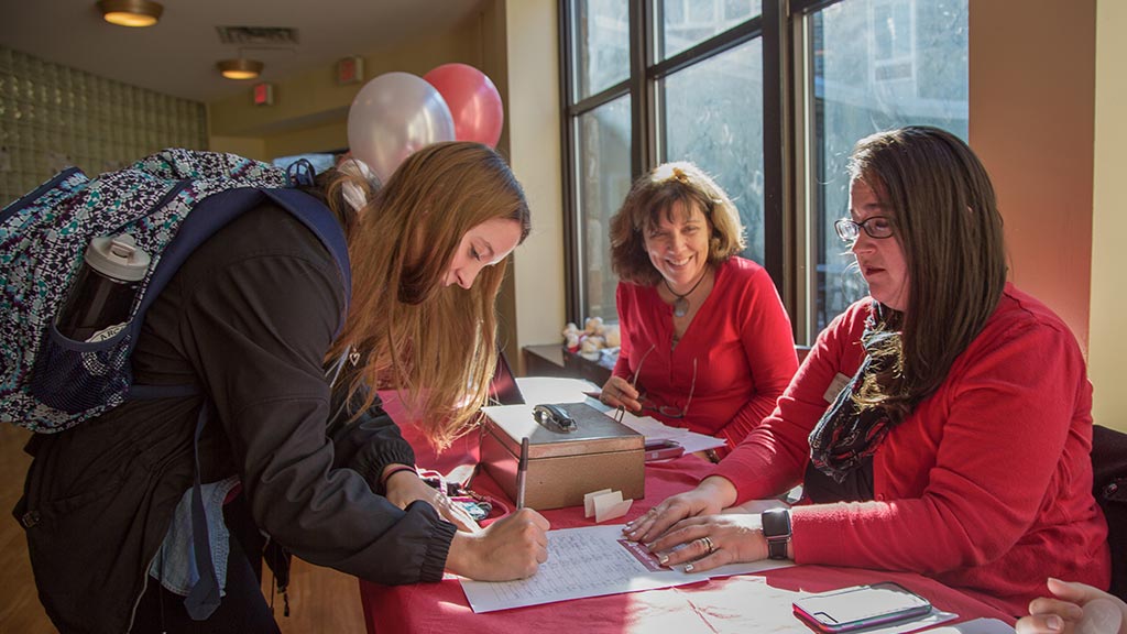 A student signs up for more information at an Arcadia event.