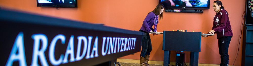 Two students enjoying competitive games in the Arcadia Game Room