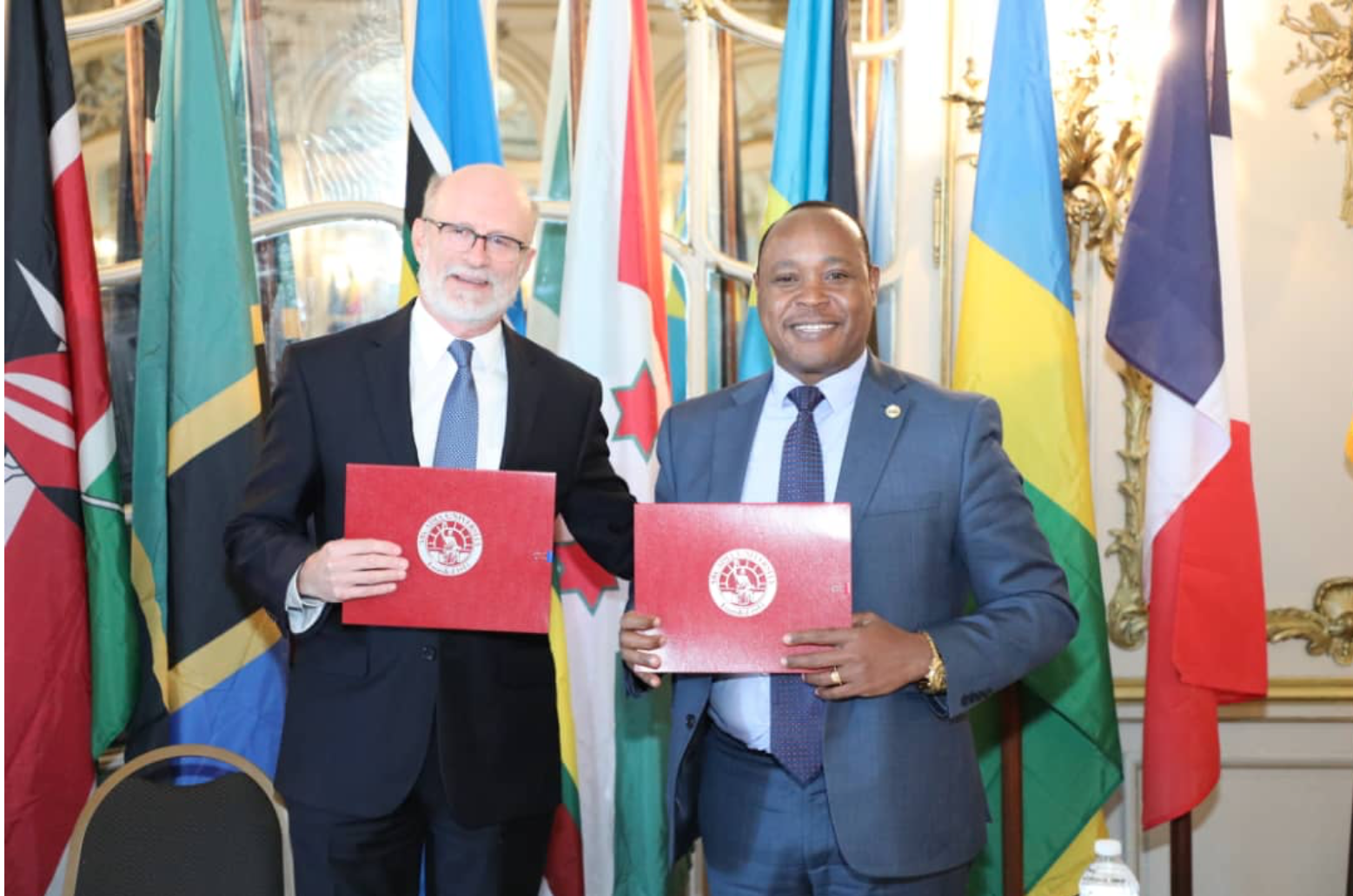 Jeff Rutenbeck and Peter Mathuki hold up the signed copies of the MOU to reopen the Nyerere Center for Peace Research.