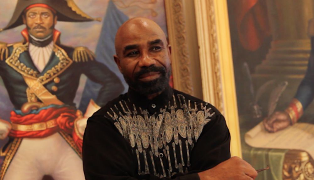 Haitian American artist Ulrick Jean-Pierre with painted artwork around him
