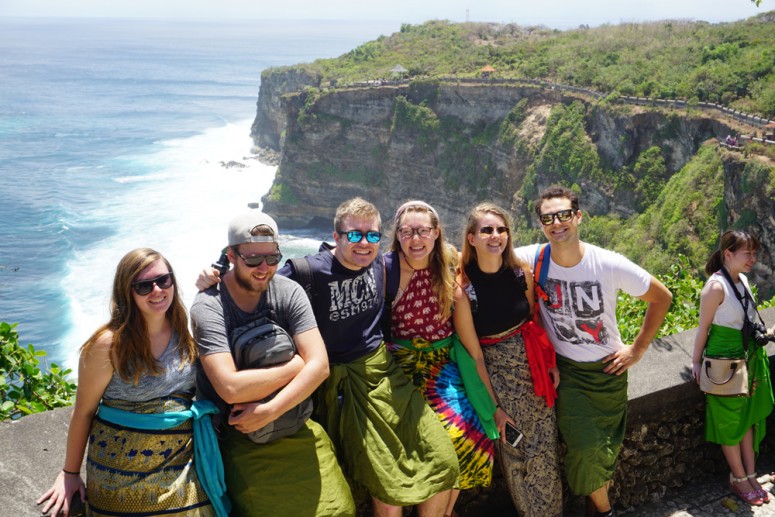 Students take a group photo on the edge of a cliff overlooking water