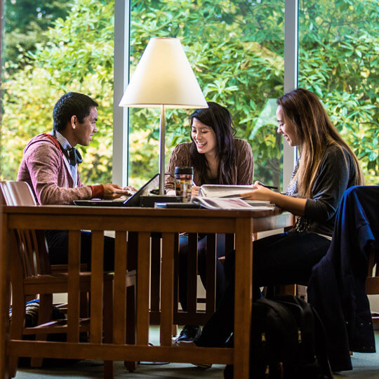 Students work together at a table lit by a lamp