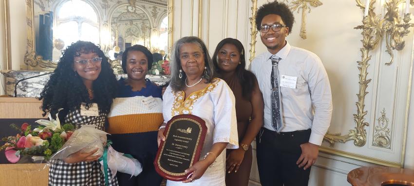 Arslie Jacques-Louis ‘24, Simone Smith ‘23, Dr. Loury, Nyla Russel ’24, and O'Shane Mendez ’24 posing together with a plaque and flowers