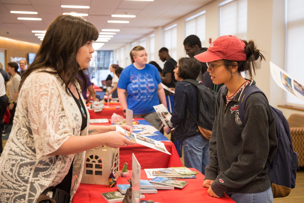 A staff member handing information to students during GFS Kickoff.