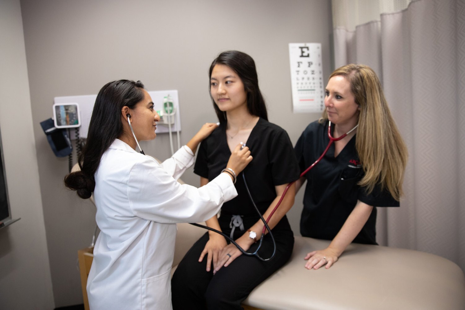 Pysicians Assistant graduate students look at a patient.