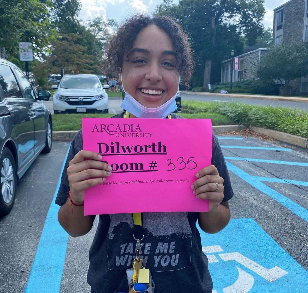 A photo of Ethan holding his room assignment on move in day.