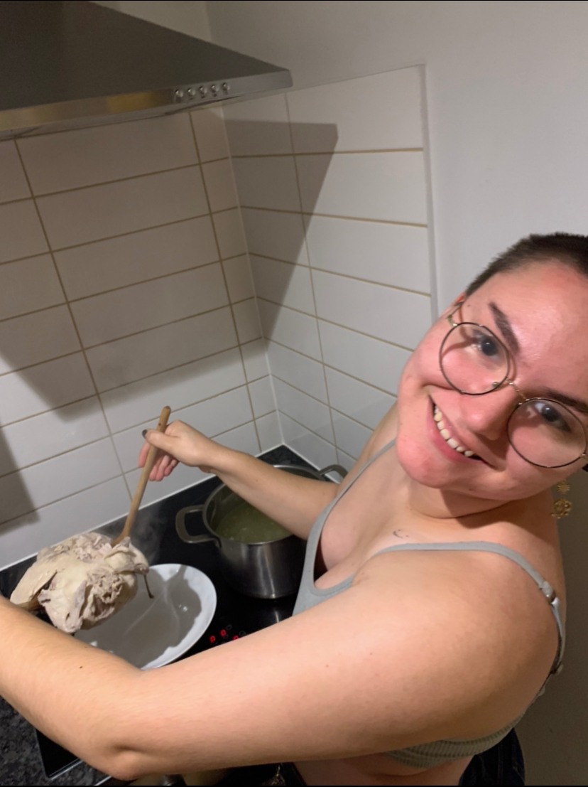 A woman smiles as she cooks on a stove