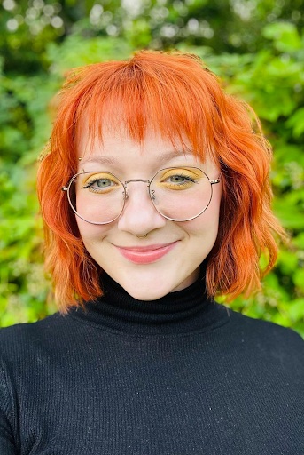 Leigh Ferrier wears glasses in an area full of greenery.