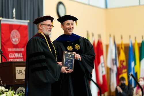 Lindback Award recipient poses with plaque in full regalia.