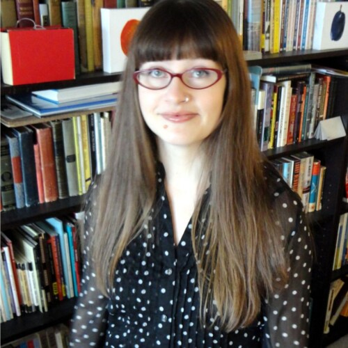 A portrait of a woman with red glasses and a polka dotted blouse