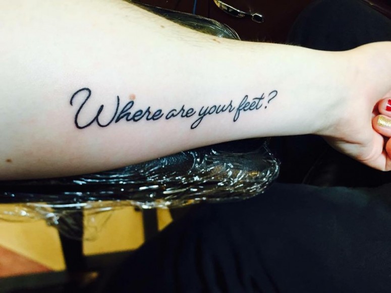 An arm showing a tattoo that is a phrase: Where are your feet?