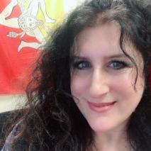 Dr. Michelle A. Reale smiles in front of a orange-yellow fabric backdrop