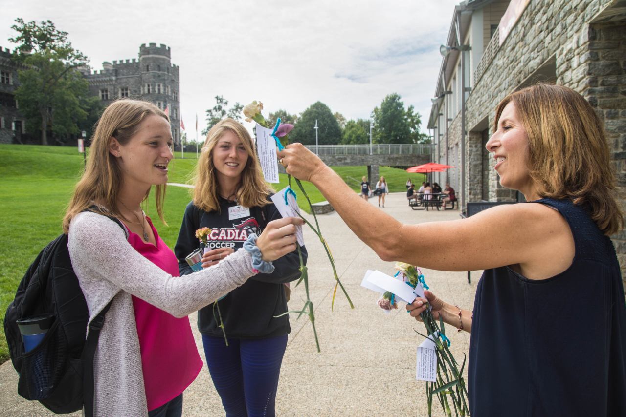 A counseling service staff handing items to students.