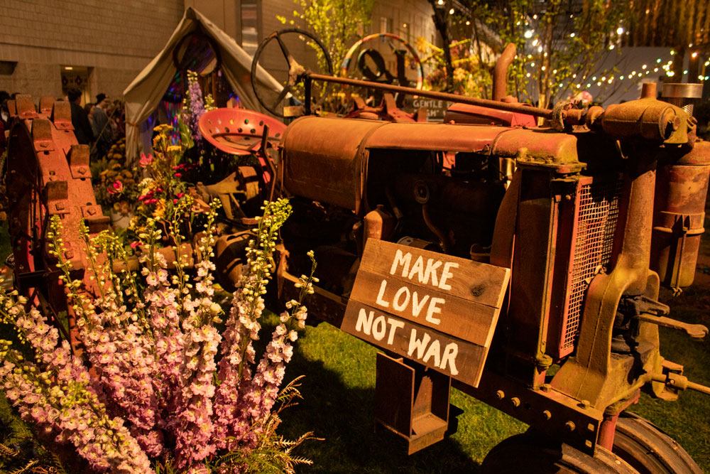 A rusty tractor holding up a sign that says: Make Love Not War.