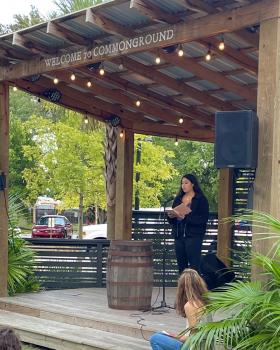 Wingfield reading poetry from a picturesque, lighted patio with forest background