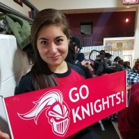 A woman holds a red banner that says "Go Knights!"