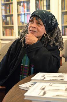 Sonia Sanchez seated at a library and leaning on a table