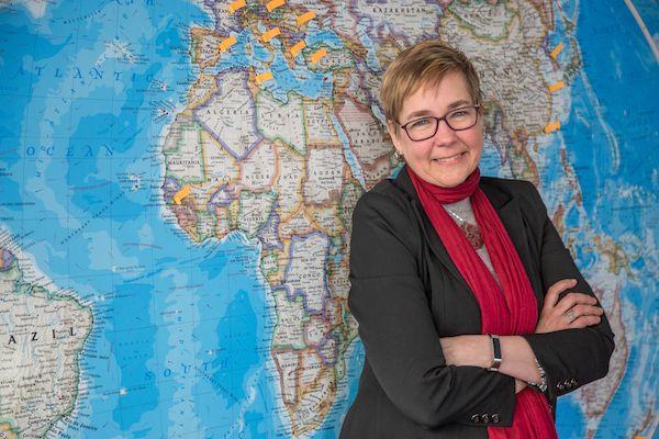 Dr. Sandra Crenshaw stands in front of a world map