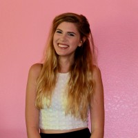 Becca Dague standing in front of a pink background and smiling