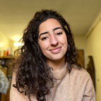 Portrait of a student with curly black hair, smiling at the camera.