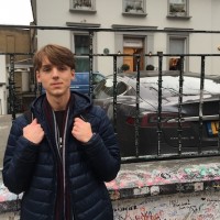 A student with a backpack stands in front of a gate