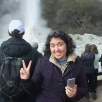 A woman giving the peace sign in front of a waterfall