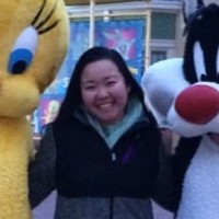 A woman standing in between a Tweety Bird mascot and a Sylvester Cat mascot
