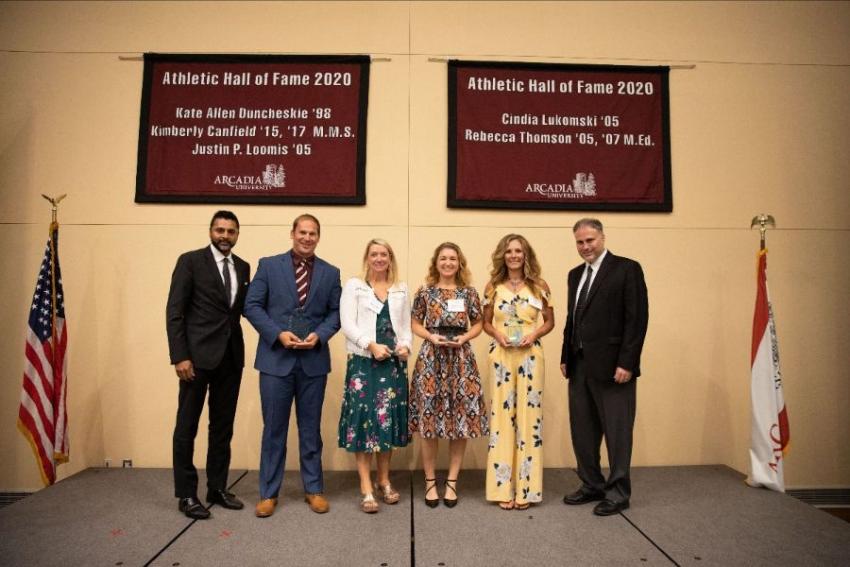 A group of people standing in front of Athletic Hall of Fame signs.