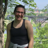 A portrait of Kaylie Rusler / a woman with trees and a bridge in the background